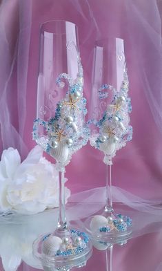 two wine glasses decorated with pearls and seashells