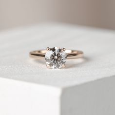 a diamond ring sitting on top of a white box with a light colored back ground