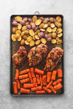 chicken, potatoes and carrots on a baking sheet with some seasoning in the middle