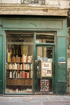 an old book store with books on display in the front window and green shutters