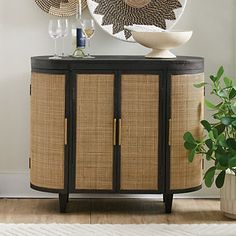 a round mirror sitting on top of a wooden cabinet next to a potted plant