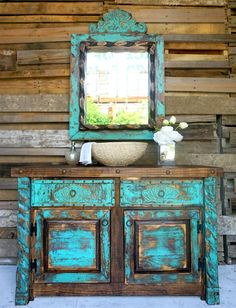 an old dresser with a sink and mirror on it in front of a wooden wall