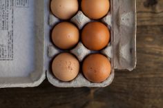 six eggs in an egg carton on a wooden table