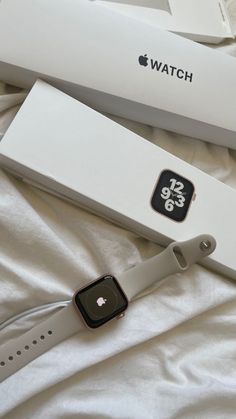 an apple watch sitting on top of a bed next to a white box and packaging