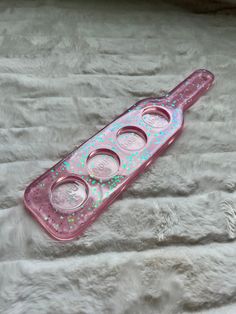 a pink plastic container with three holes in it sitting on a white fur covered surface