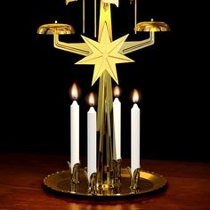 a golden candle holder with five lit candles in the shape of a star on a wooden table