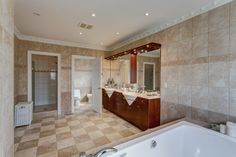 a large bathroom with tiled floors and walls, along with a bathtub in the middle