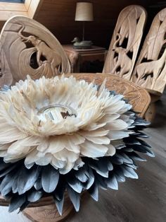 a white and black flower sitting on top of a wooden table next to two chairs