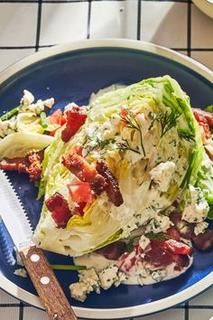 a blue plate topped with lettuce and bacon next to a knife on a table