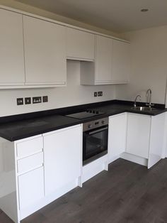 an empty kitchen with white cabinets and black counter tops on the island in front of the stove