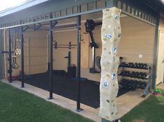 a home gym is shown in the backyard with an exercise wall and equipment on display