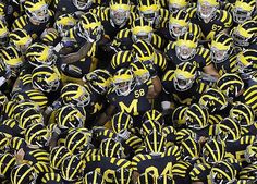 a large group of football players in black and yellow uniforms with numbers on their helmets