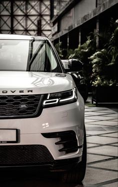 the front end of a white range rover parked on a tile floor next to a building