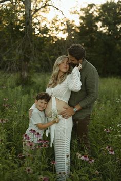 a man and woman pose for a photo with their son in a field full of flowers