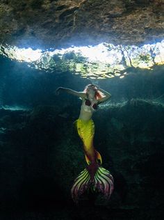 a woman is swimming in the water with a fish