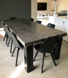 a dining room table with black chairs and a television in the background