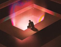 a man sitting in the middle of a room with colored light coming from behind him