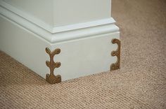 the corner of a room with carpeting and a white column on the floor next to it