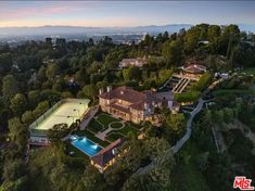 an aerial view of a mansion with a tennis court in the foreground