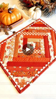 a quilted table runner with pumpkins and other autumn decorations