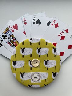 four playing cards are sitting on top of a yellow case with sheeps and hearts