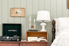 a suitcase sitting on top of a wooden dresser next to a bed with white sheets