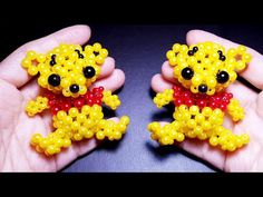 two small yellow bears with black eyes and red bows in their hands, made out of beads