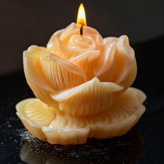 a close up of a candle on a black surface with water droplets around the candles