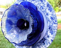 blue and white plates stacked on top of each other in the middle of a yard