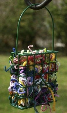 a bird feeder filled with lots of colorful yarn