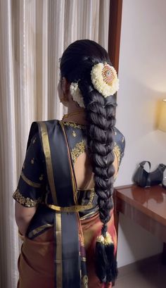 a woman with long braids and flowers in her hair is looking out the window