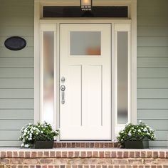 a white front door with two planters on the step and a light above it