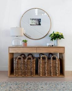 a wooden table with baskets under a round mirror