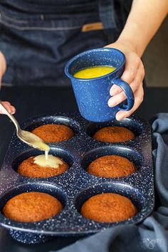 a person is dipping some food into a muffin pan with other muffins in it