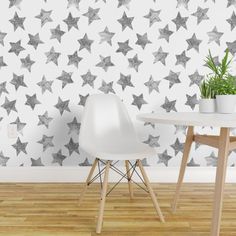 two white chairs and a table in front of a wall with silver stars on it