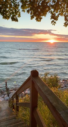 the sun is setting over the water and there are wooden steps leading up to it