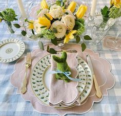 the table is set with yellow flowers and white plates, silverware, and napkins