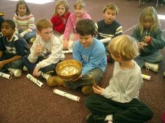 a group of children sitting on the floor in front of each other with bowls and spoons