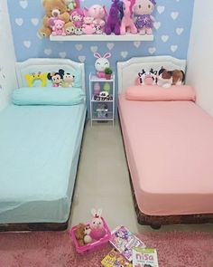 two twin beds with pink and blue sheets in a room filled with stuffed animal toys