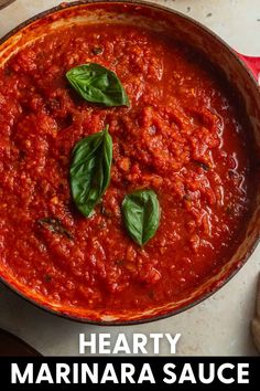 a skillet filled with marinara sauce and topped with basil leaves on the side