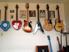 guitars are lined up on the wall in this room