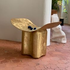 a gold bench sitting on top of a brick floor next to a white vase and potted plant