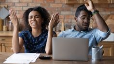 a man and woman sitting at a table with their hands up in front of them