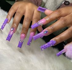 a woman's hands with purple and white nail designs on their nails, while she is sitting down