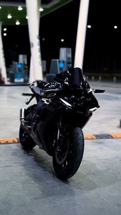 a black motorcycle parked in front of some gas pumps at an empty gas pump station