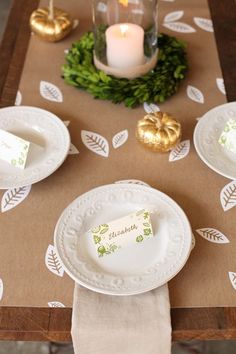 a table set with plates, napkins and candles