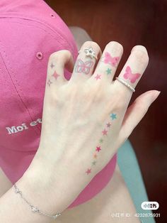 a person with tattoos on their fingers and hand wearing a pink baseball cap behind her