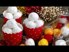 two red buckets filled with snowballs sitting on top of a wooden table next to flowers