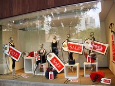 a window display with mannequins and sale signs