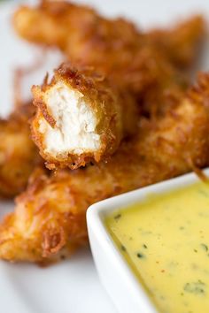 some fried food on a white plate with dipping sauce